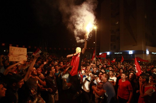A demonstrator holds up a flare during a protest to demand the ouster of the Islamist-dominated government in Tunis